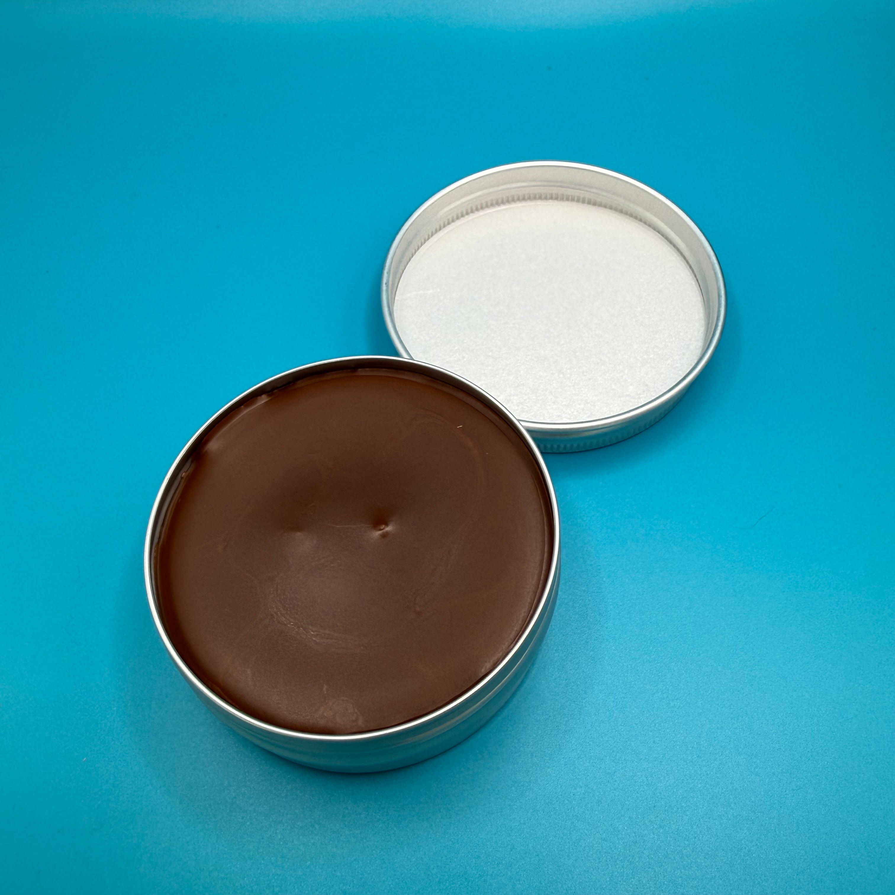Open tin 'Fire Horse Botanicals' balm on a blue background.
