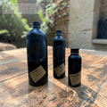 Three black bottles with labels on a wooden surface, featuring 'Fire Horse Botanicals' branding.