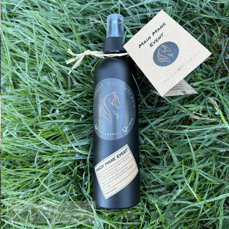 Bottle of 'Fire Horse Botanicals' product on grass with a tag.