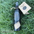 Bottle of 'Fire Horse Botanicals' product on grass with a tag.