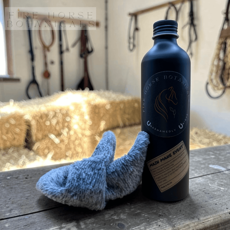 Black bottle with label and grey cloth on wooden surface in a stable, 'Fire Horse Botanicals' branding.
