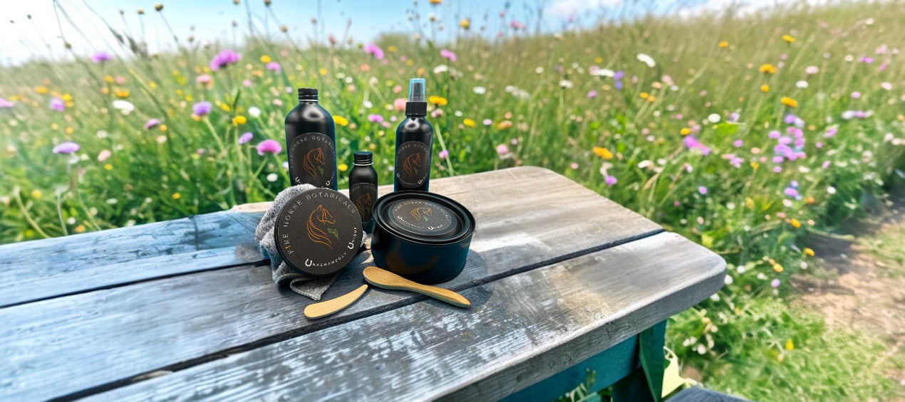Fire Horse Botanicals products on a wooden bench with a natural background of flowers and grass.