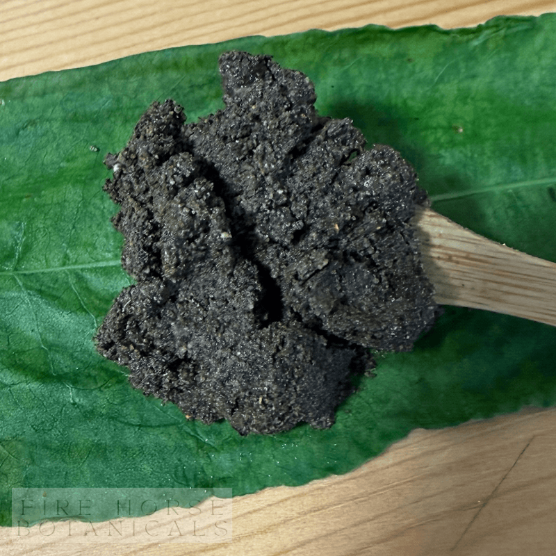 Putty mixed for use on a wooden spoon over a green leaf with 'Fire Horse Botanicals' branding.