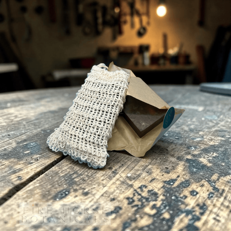 Soap bar with sisal bag on a wooden surface with a workshop background and 'Fire Horse Botanicals' branding