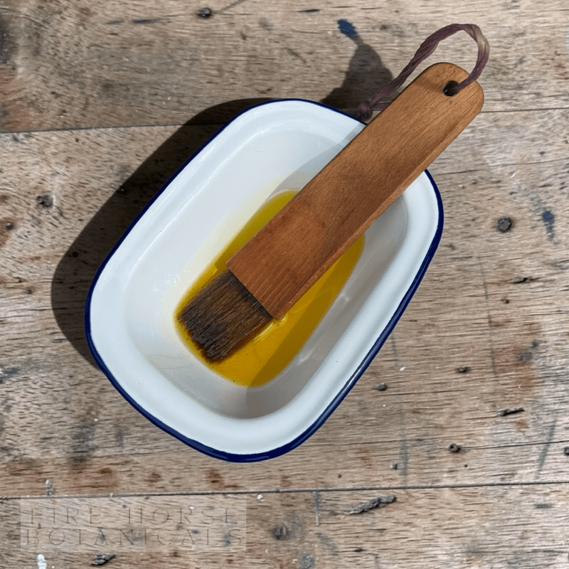 Wooden brush in a container of 'Fire Horse Botanicals' product on a wooden surface