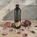 Bottle of Fire Horse Botanicals product on a wooden surface with dried roses and petals.