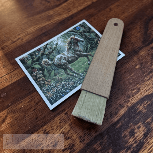 Wooden brush with a 'Fire Horse Botanicals' postcard on a wooden surface